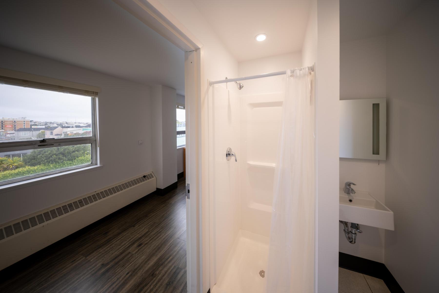 Bathroom in a Nagle bedroom, including a curtained shower stall and a sink with a mirror