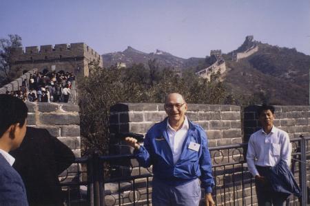 Smiling man standing in front of the Great Wall of China, surrounded by tour group
