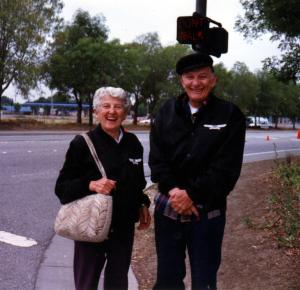 A woman and a man standing next to each other on a sidewalk, smiling