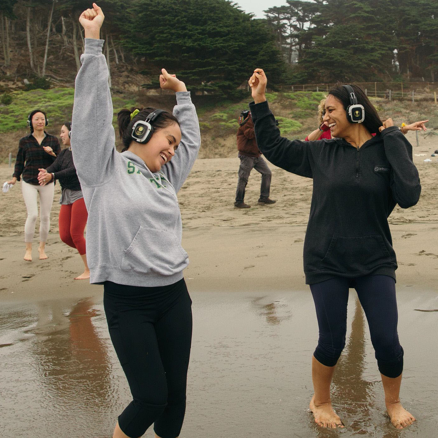 Two students dancing at baker beach with headphones on