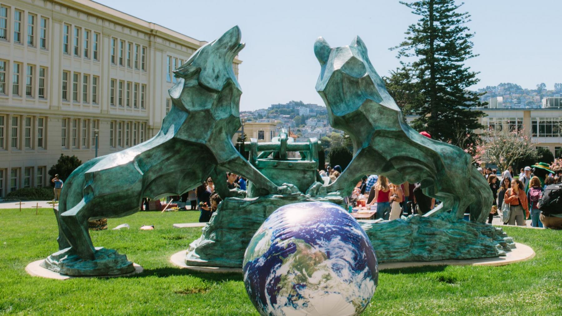 Giant earth ball next to wolf and kettle statue at USF