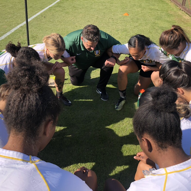 rugby players and coach kneeling on field praying