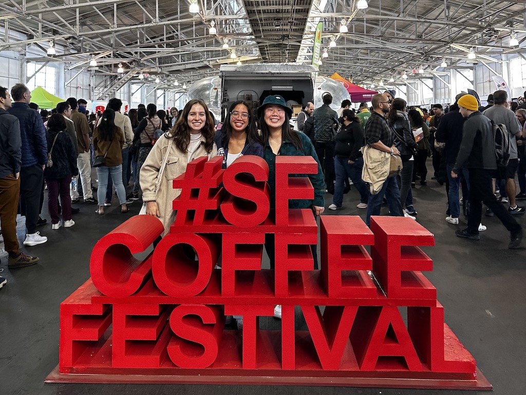 3 students smiling in front of the #sf coffee festival sign