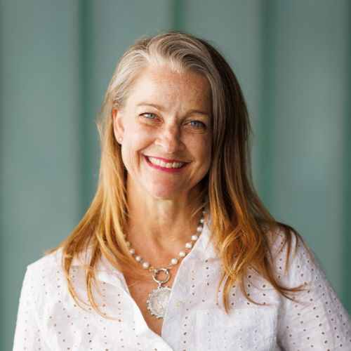 "caucasian woman with red lipstick smiling with her hair down and looking at the camera, in front of a seafoam green background"