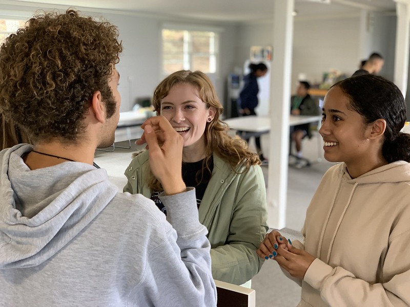 Three students smiling as they play a game together.