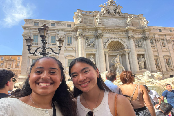 Two female presenting students smiling in front of Trevi Fountain
