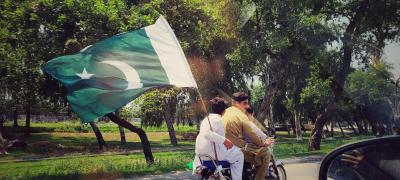 Man on motorcycle holding pakistani flag