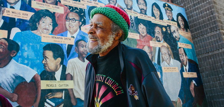 Man standing in the Mission in front of mural