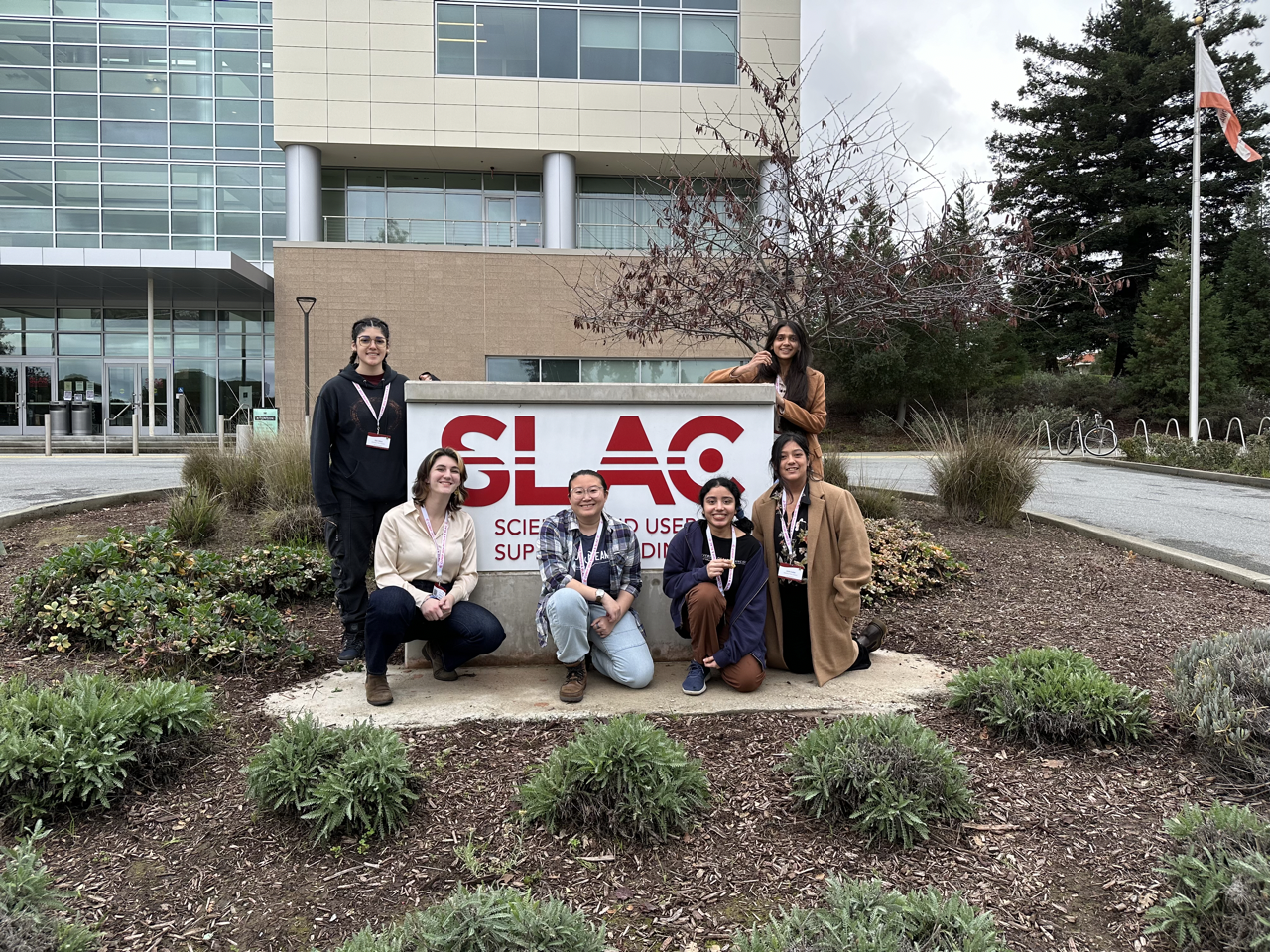 Physics students standing in front of Stanford's SLAC facility sign.