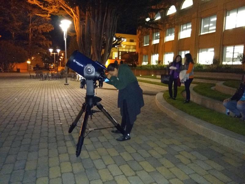 student looking through a telescope at night