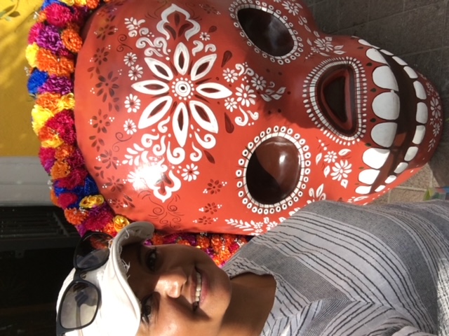 Woman next to red Mexican-decorated skull
