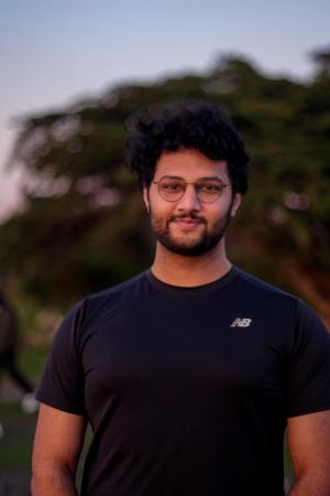 Student standing and smiling with sky as the background