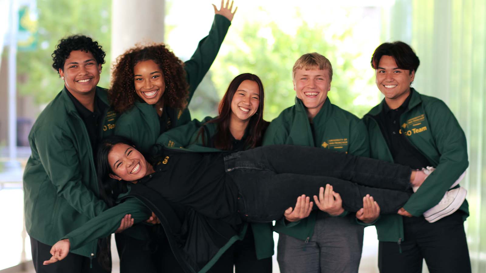 Five students holding one student