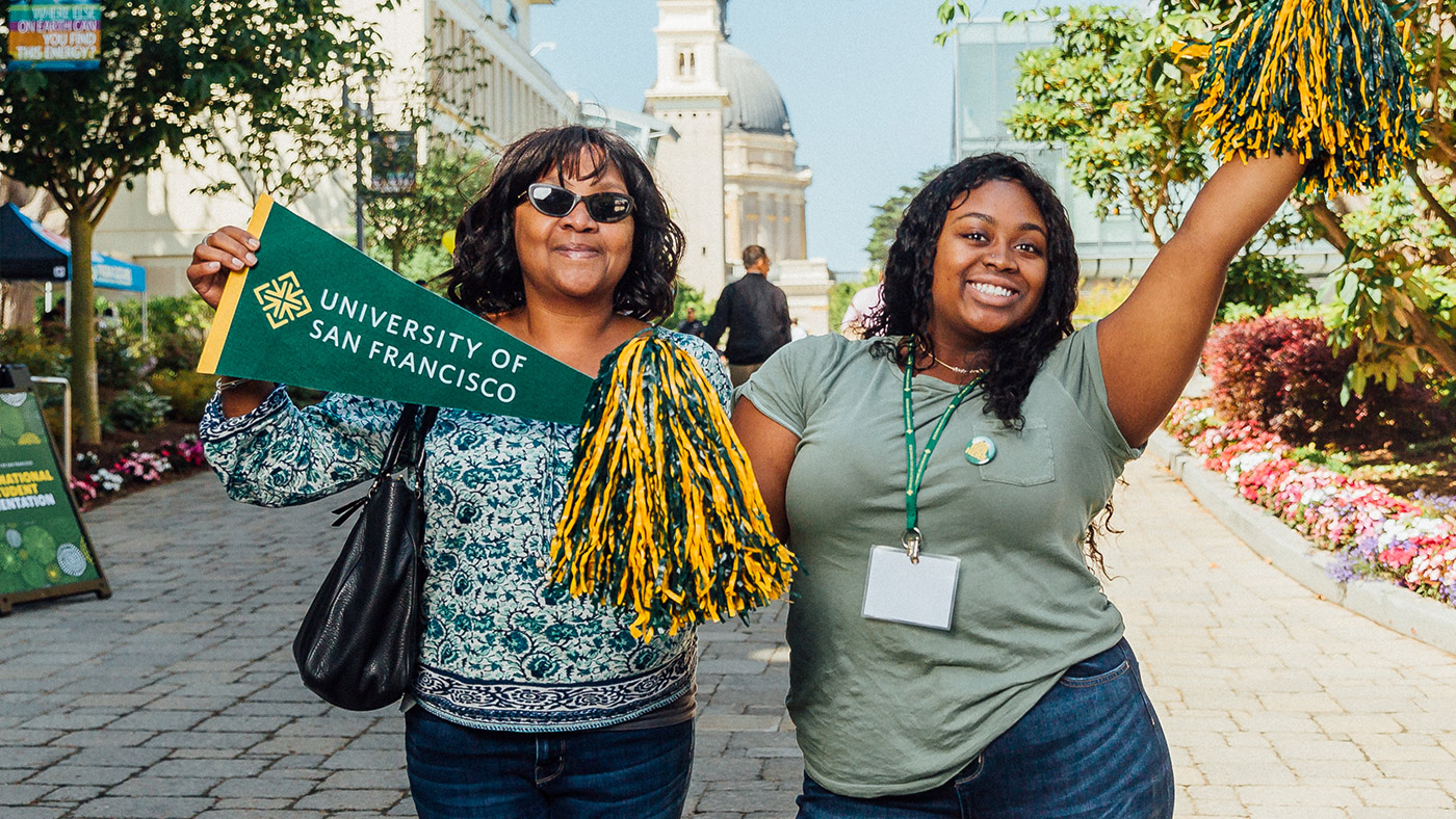 Family members hold USF pennant and pom-pom